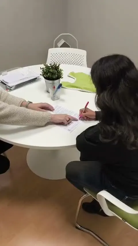 Due persone firmano dei documenti a un tavolo nella sede Cocoon